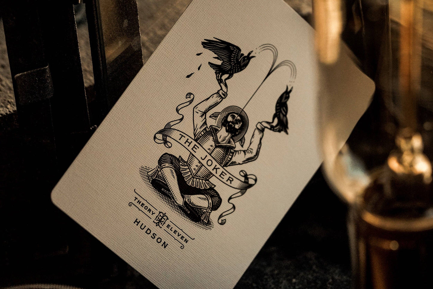 Playing card featuring 'The Joker' design with decorative elements on a textured surface.